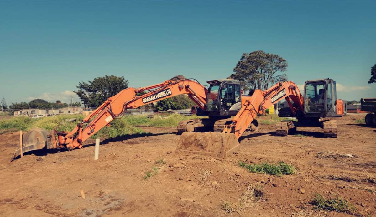 Excavators at a construction site with Graham Harris branding in New Zealand.