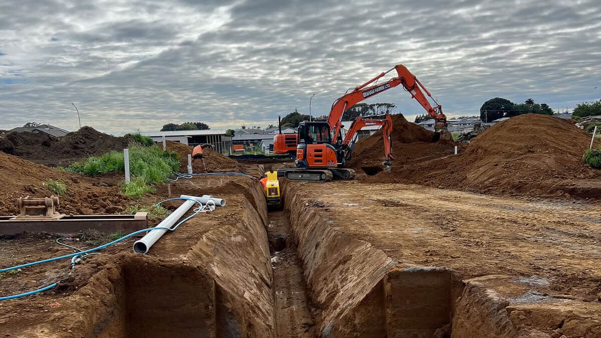 Excavator working on underground piping and trenching for construction projects in New Zealand.