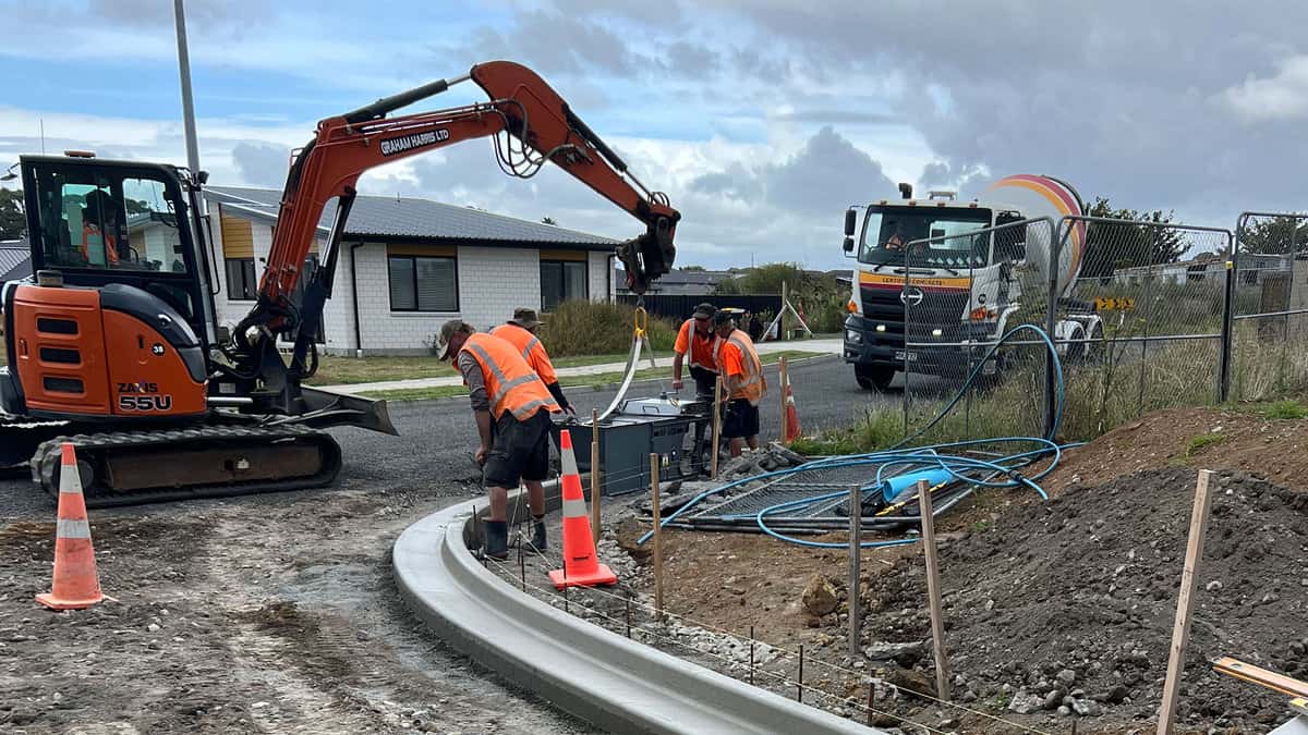 Heavy construction work happening on road with workers and machinery.