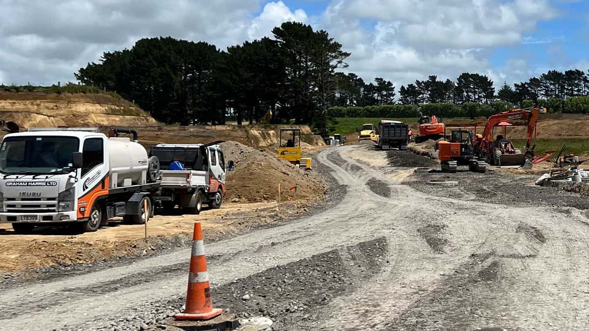 Construction site with machinery and vehicles working on road development in New Zealand.