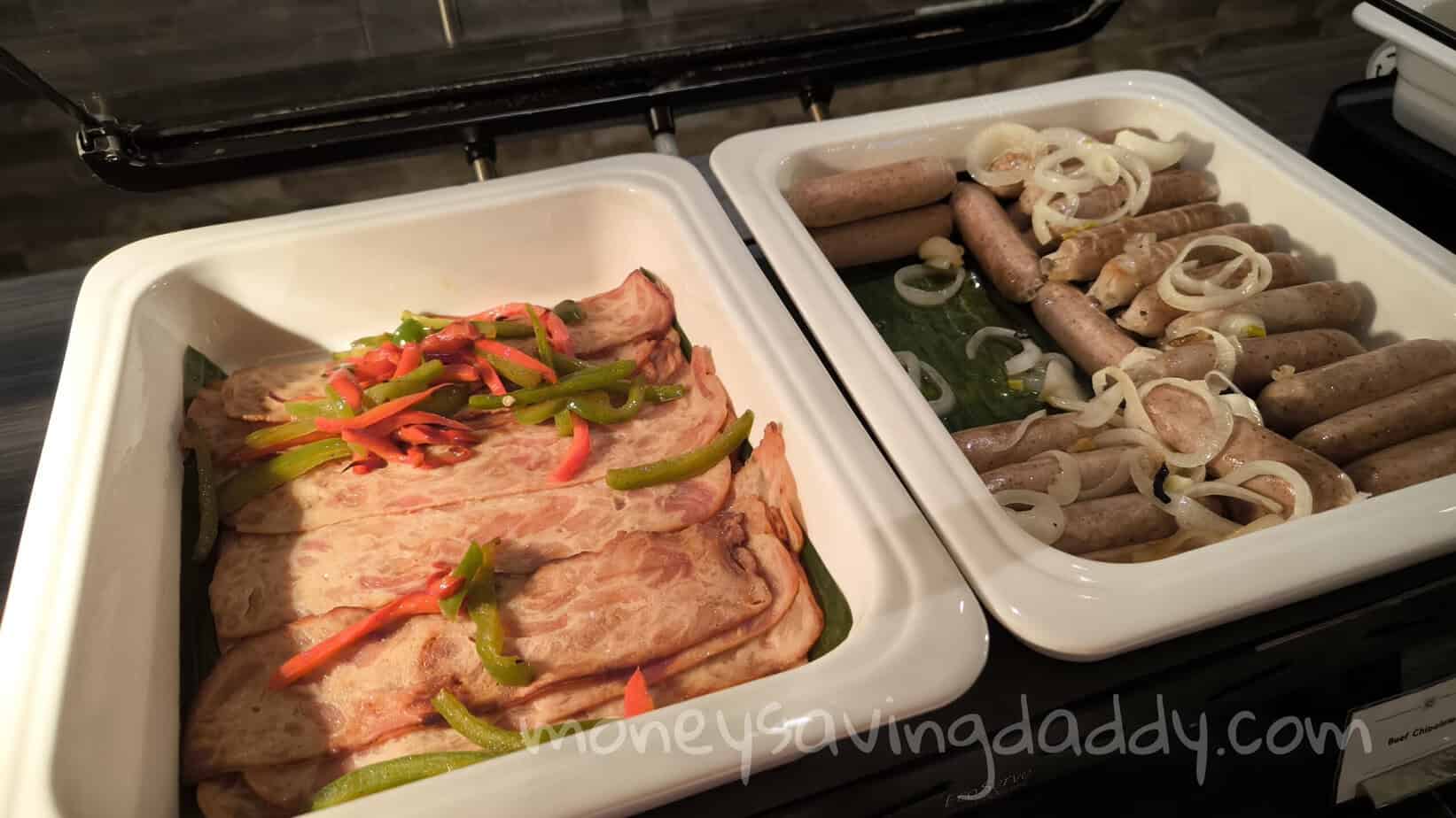 Grilled meat with sliced onions and peppers in a white container, ready for cooking or serving.
