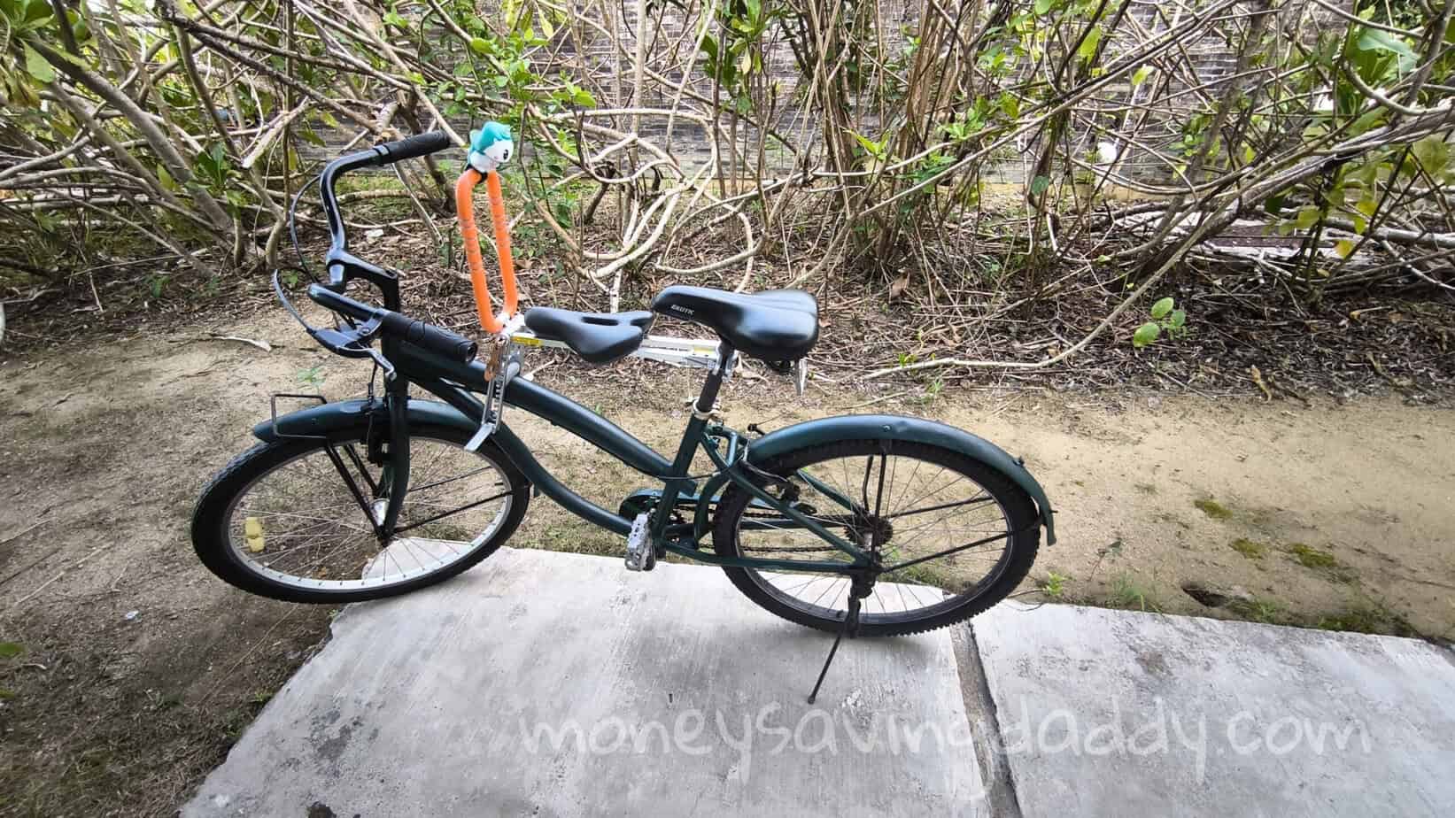 A bicycle parked on a concrete slab in a natural outdoor setting with bushes in the background.