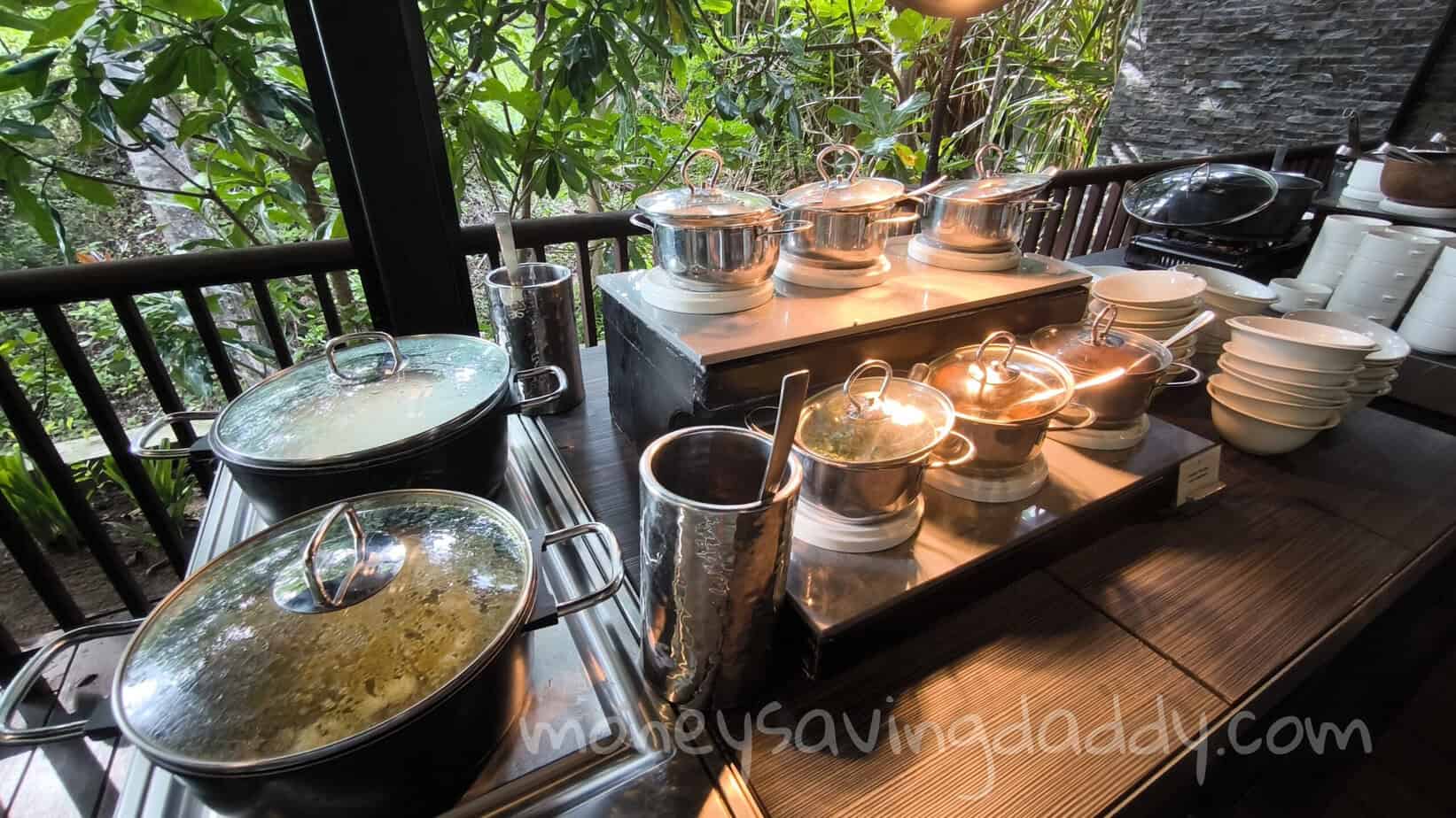 Freshly prepared hot dishes in stainless steel pots on a buffet table at a restaurant.
