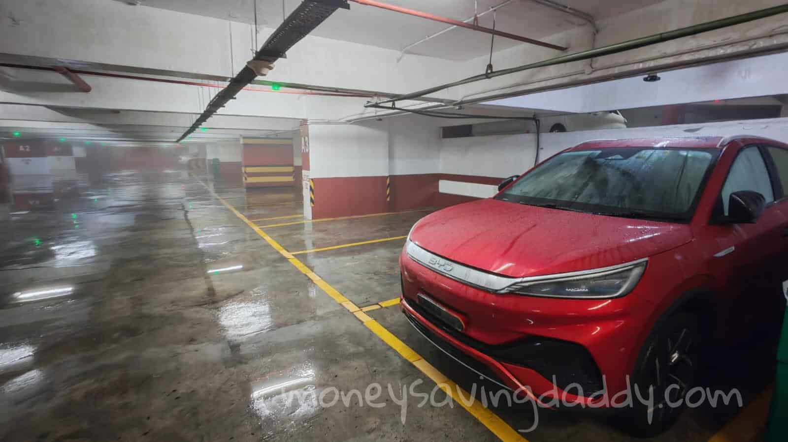 A red electric car parked in an underground parking garage.
