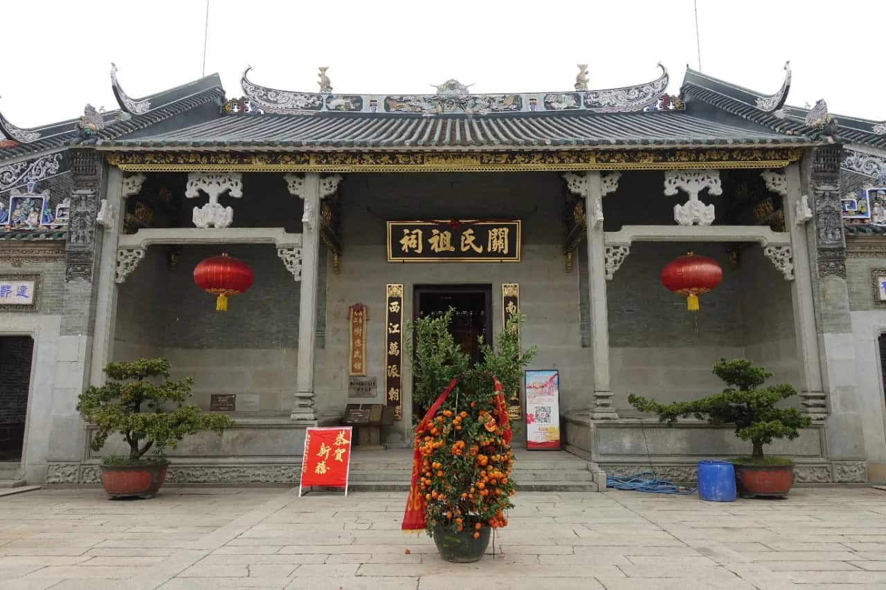 The entrance of the Guan Clan Ancestral Hall, showcasing traditional Chinese architecture with ornate roof carvings and red lanterns.
