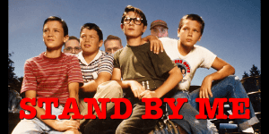 Group of five young boys sitting outdoors, with one boy in the center wearing glasses, under a clear.
