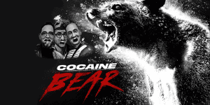 Three hosts discussing the movie Cocaine Bear with a roaring bear graphic in the background.