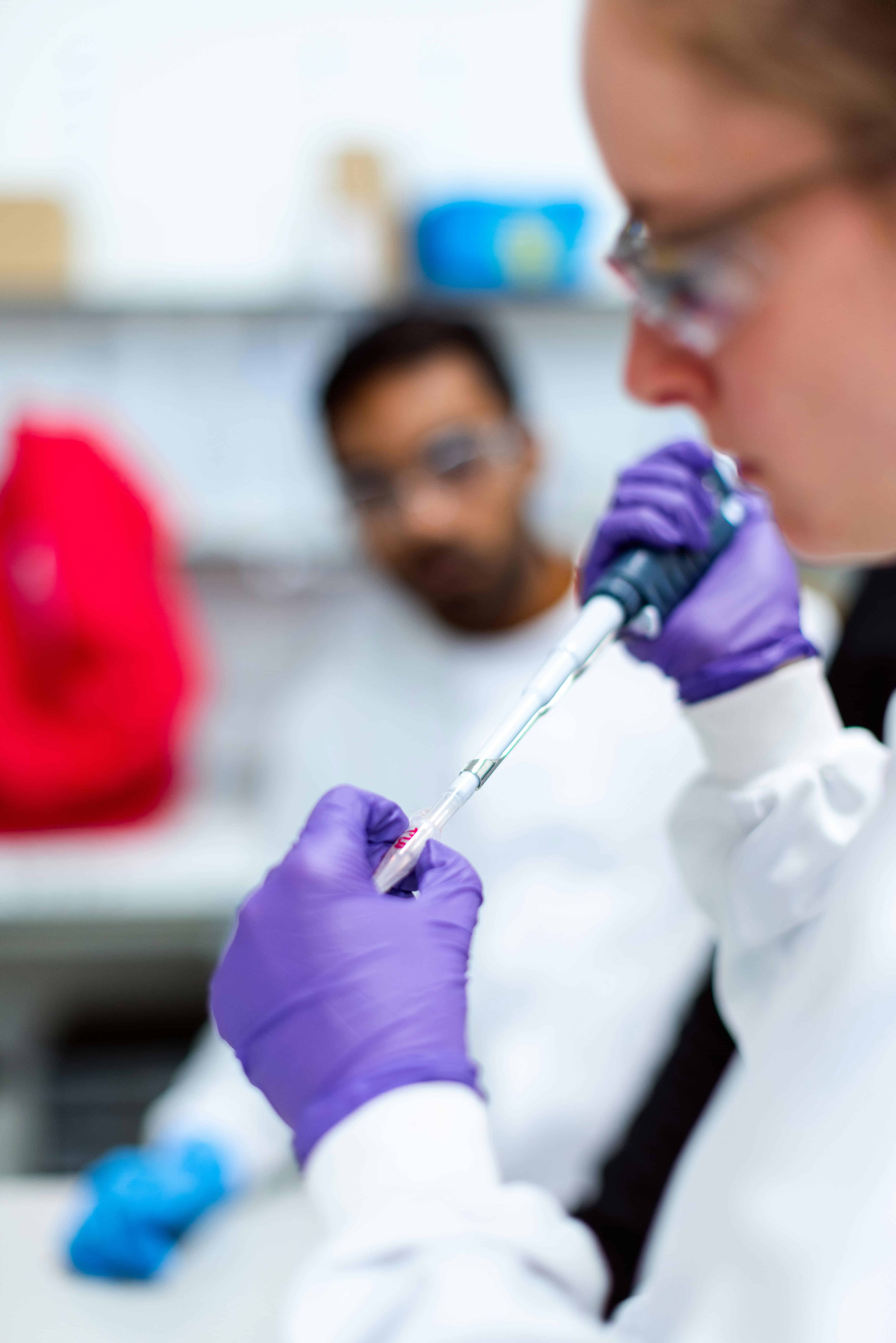 Female scientist using pipette for research in modern laboratory setting.