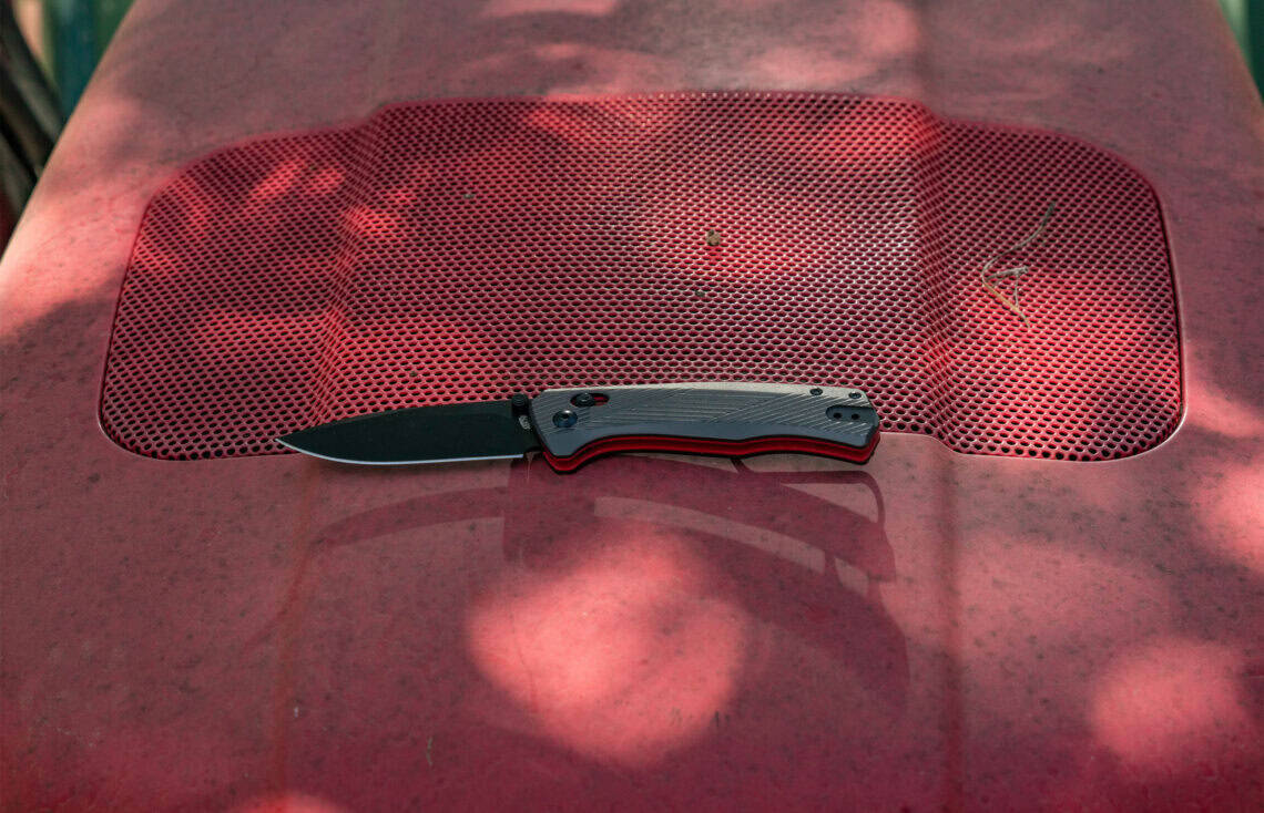 ABKT folding knife with a grey and red textured grip and black tactical blade. Premium folding tool for outdoor and daily use.