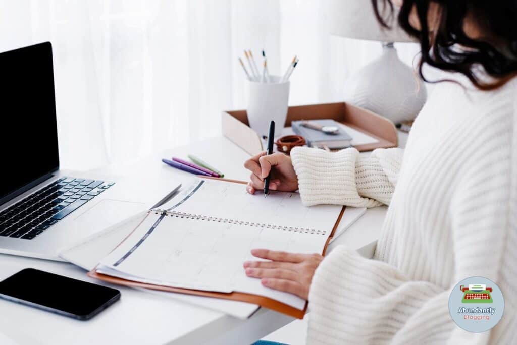 lady sitting behind her desk and writing in her blog content calendar