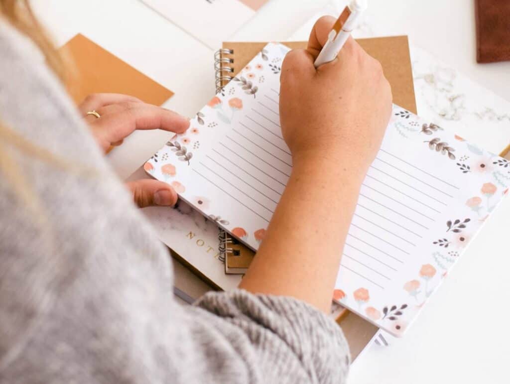 Focused woman taking notes in a journal - how to blog consistently