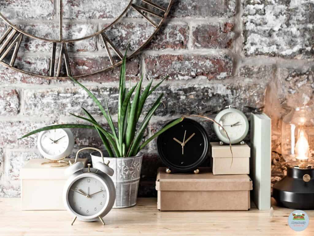 rustic wall with big metal analog clock, wooden side table, a plant, box, and 4 analog alarm clocks - pomodoro technique