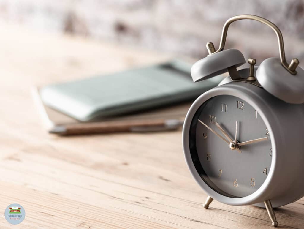 rustic wall, wooden side table, a notepad and pencil, and an analog alarm clock - pomodoro technique