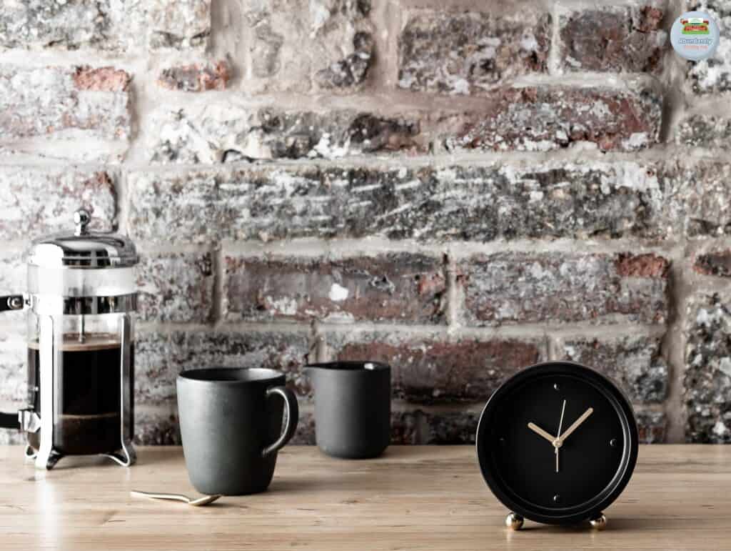 rustic wall with wooden side table, 2 mugs, a coffee pot, and 1 analog alarm clock - pomodoro technique