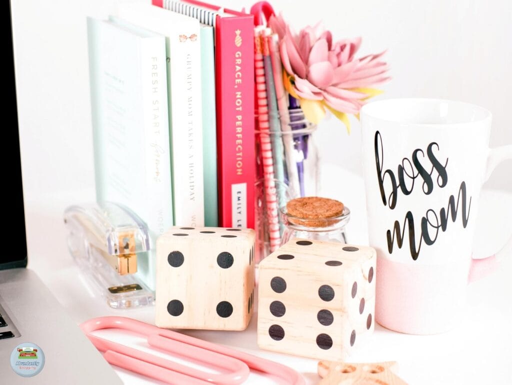 a boss mom mug, several books and notebooks, office supplies, and an open laptop on a white desk - Benefits of Work-Life Balance
