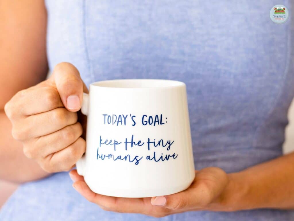 Savoring a cozy moment with her favorite coffee mug. On her mug: today's goal, keeping the tiny humans alive - Benefits of Work-Life Balance