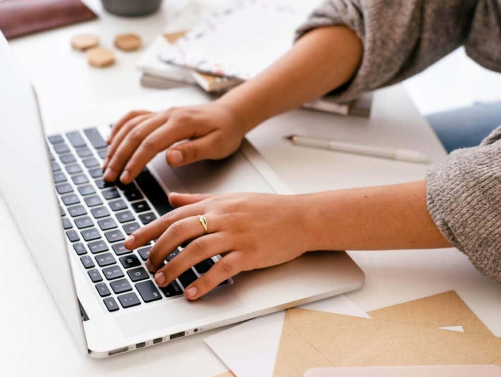 woman, behind her desk, typing on her laptop - how to blog consistently