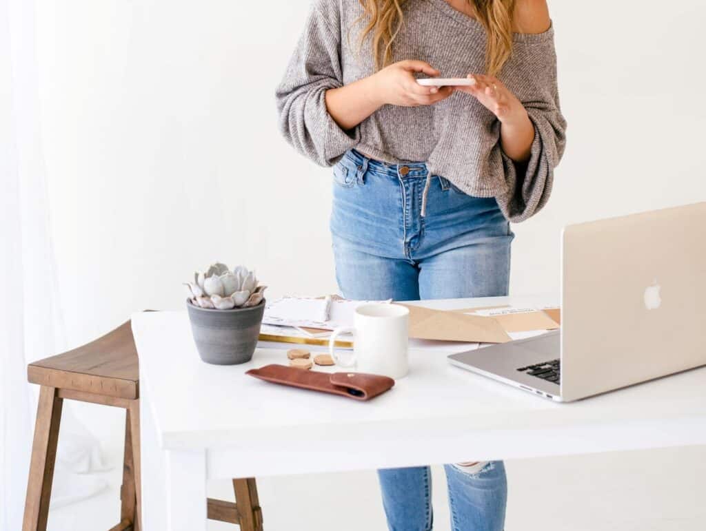 woman behind her desk taking a photo from her notebook - how to blog consistently