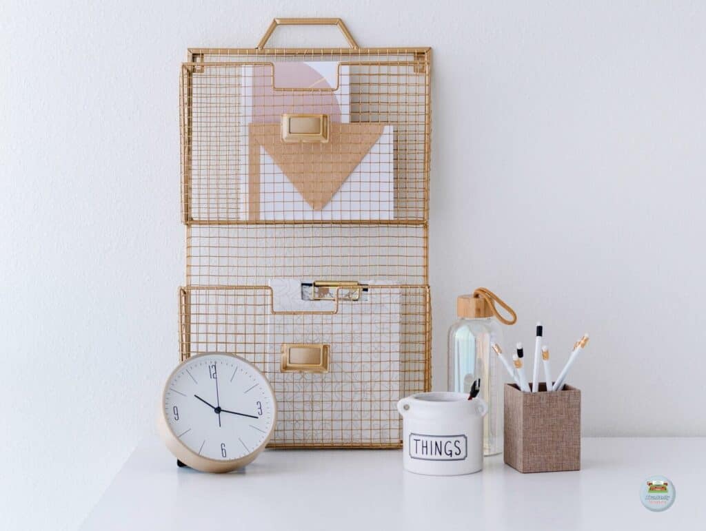 A white desk against the wall with various tools and supplies like an analog clock, a folder rack, pencils and more - 80/20 Rule in Blogging