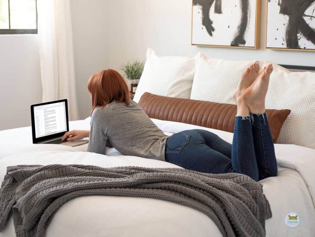 a woman lying on her bed on her stomach working on her laptop on a document - How to repurpose