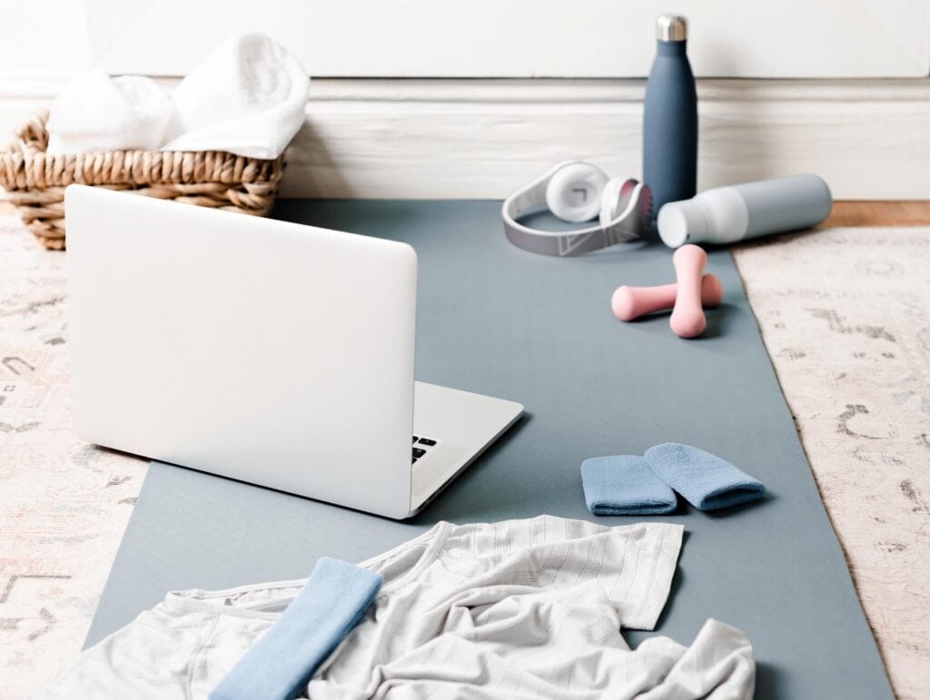 a yoga mat with a laptop and some exercise equipment - morning routine for bloggers