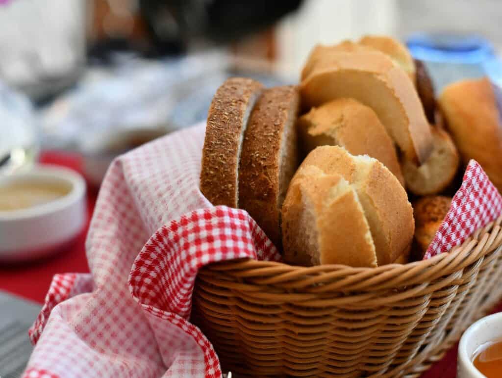 a basket with a checkered towel and slices of break on a breakfast table - morning routine for bloggers