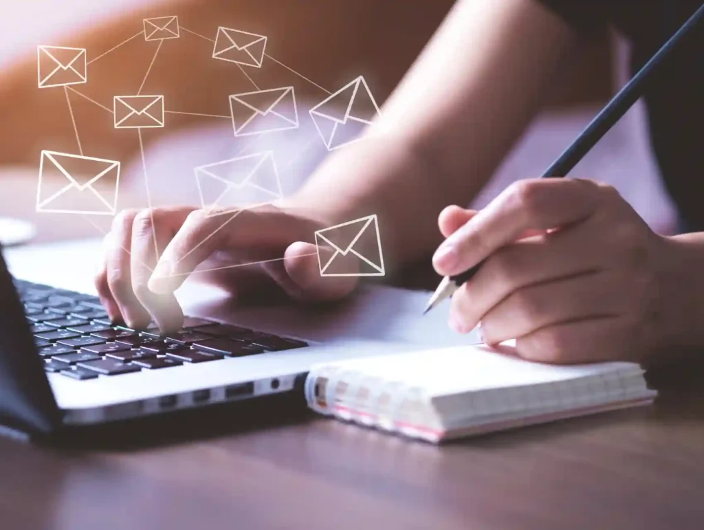 an close-up image of two woman's hands working on a laptop and holding a pencil over a notebook - email list goals
