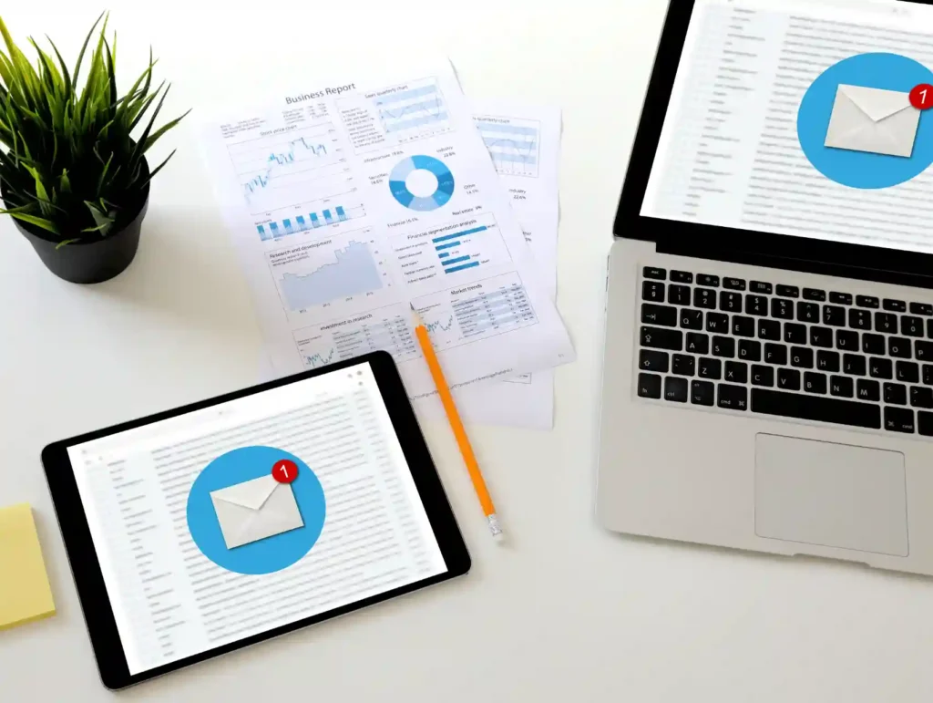a laptop, a tablet, some paper, a pencil, and a plant on a desk - email list goals