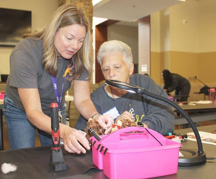 Lynn assists an older adult with assistive technology.