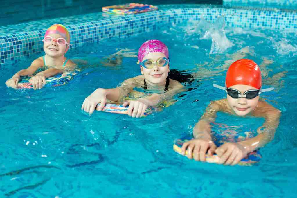 Group of boys and girls train and learn to swim in the pool with an instructor.