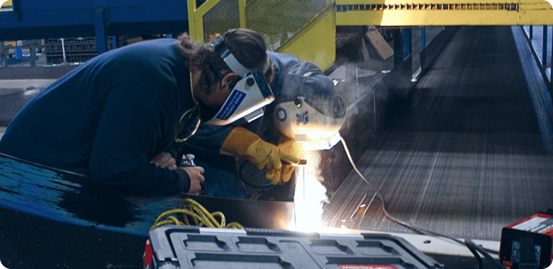 service technicians welding a conveyor belt in a factory
