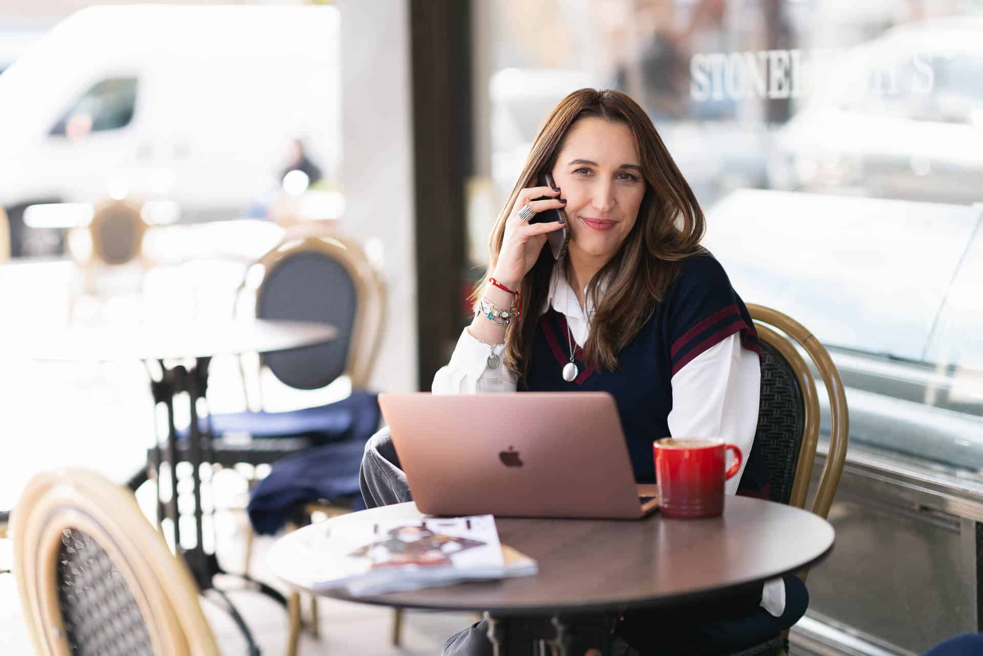 Maria Rolles, founder of Ads Couture, taking a business call at an outdoor café.