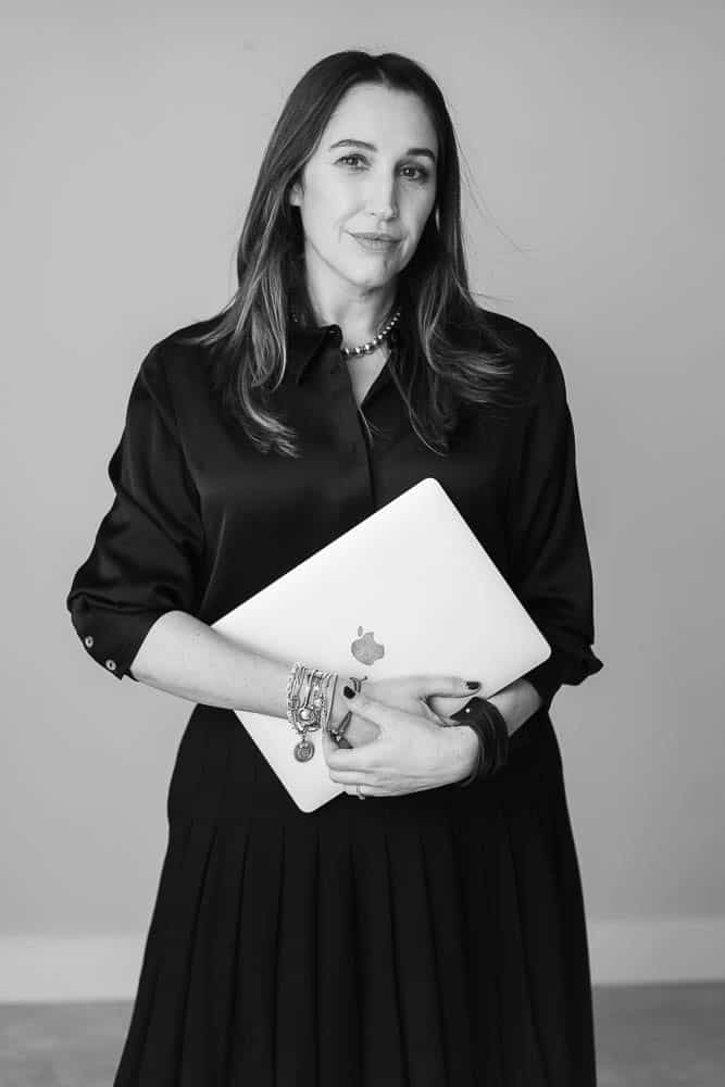 Black and white portrait of Maria Rolles, founder of Ads Couture, holding her laptop.