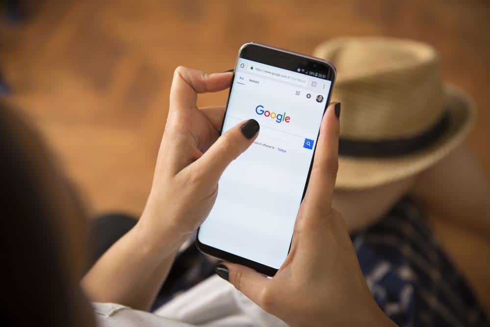 Close-up of a person holding a phone displaying the Google page, representing Google Ads advertising.