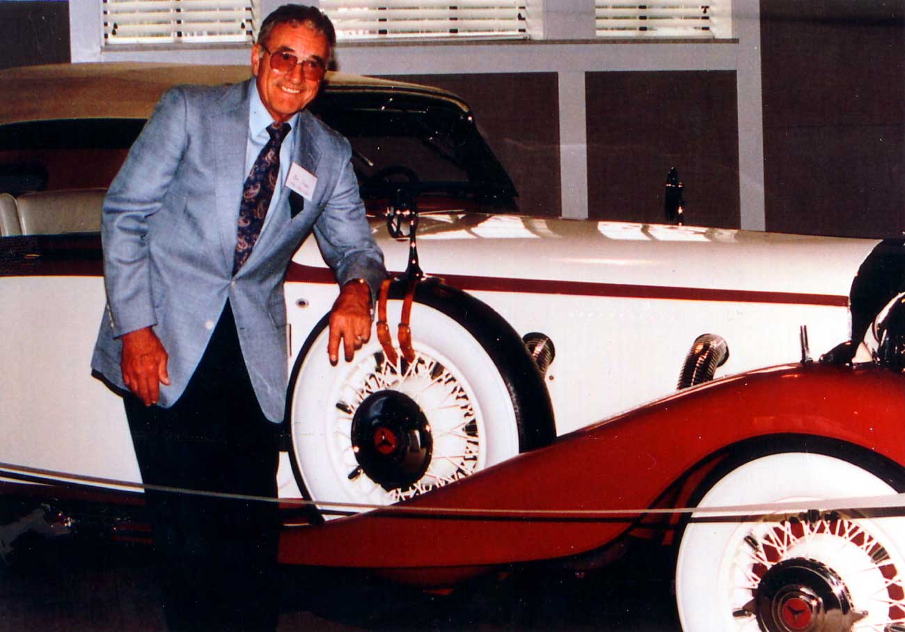Man in suit beside vintage classic car