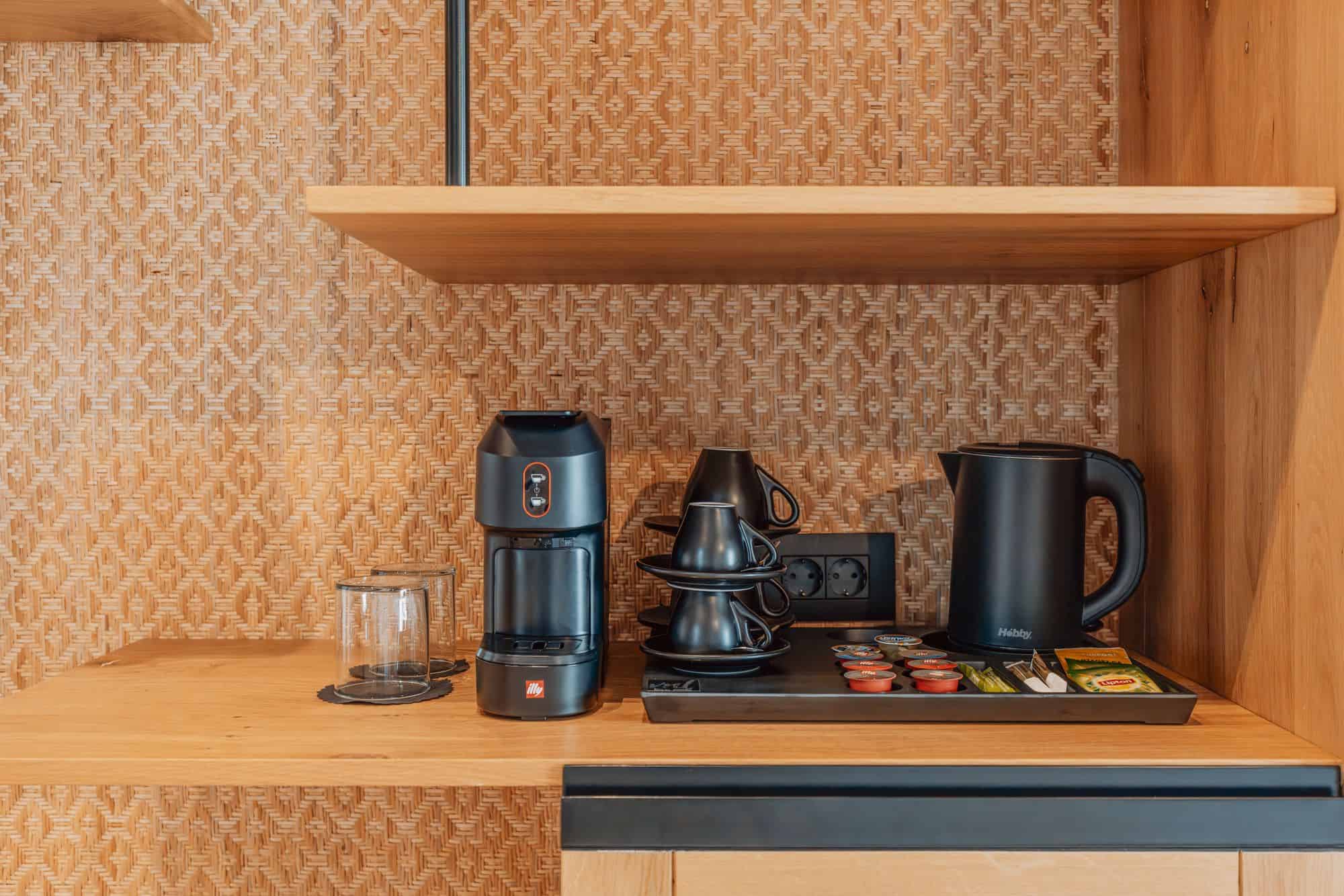 Modern kitchenette with coffee maker, electric kettle, cups, and tea bags in stylish accommodation.