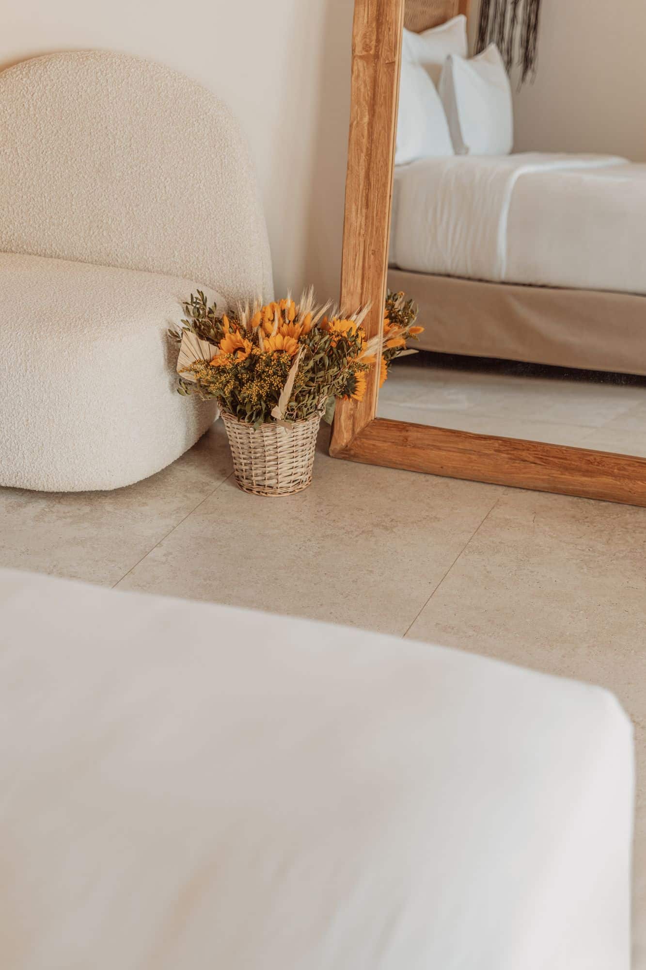 Bright interior with comfortable bed, stylish mirror, and vibrant sunflower bouquet in wicker basket.