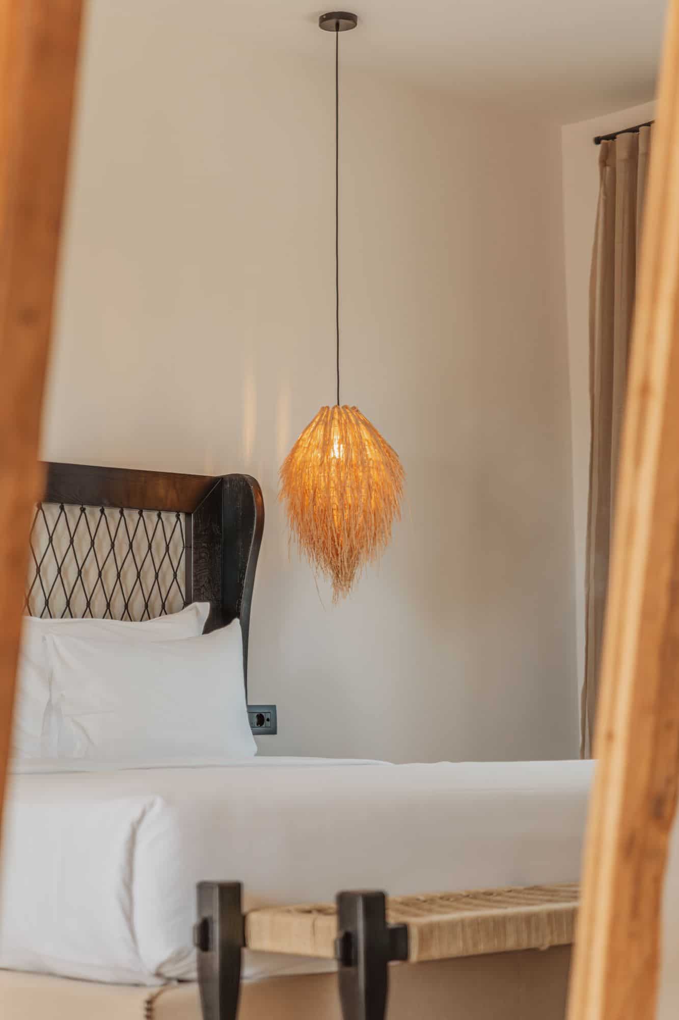 Beautiful interior of a Mykonos hotel room featuring cozy bedding and stylish lighting fixture.