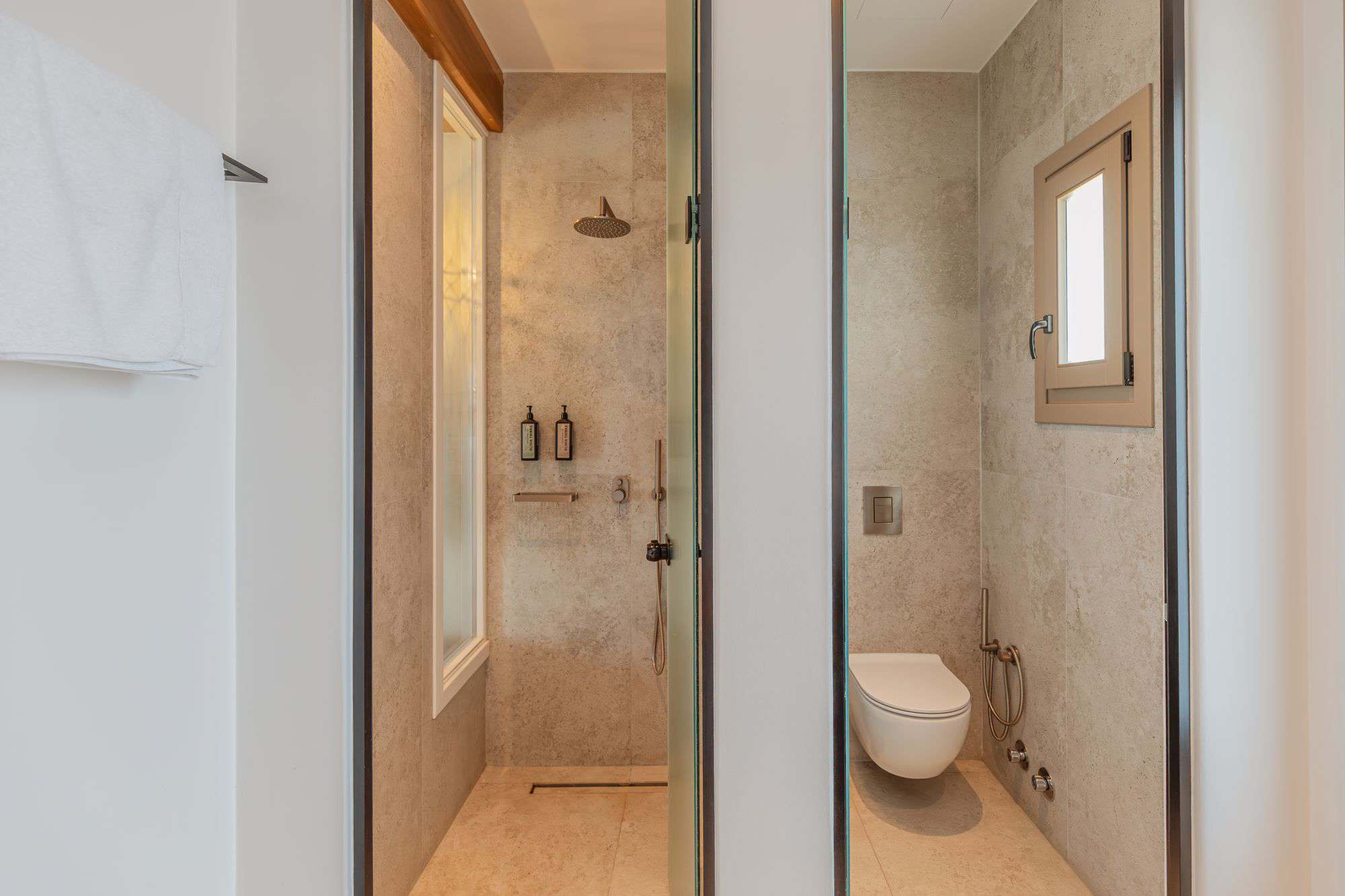 Modern bathroom in Mykonos hotel with shower, toilet, and natural light.