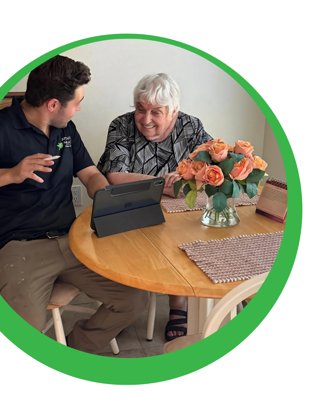Man and woman looking at a tablet on a wooden table with flowers.