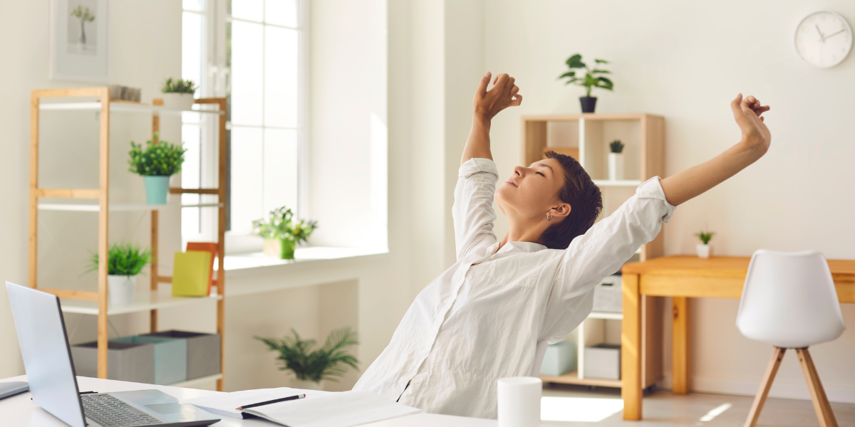 Woman stretching at desk in bright home office