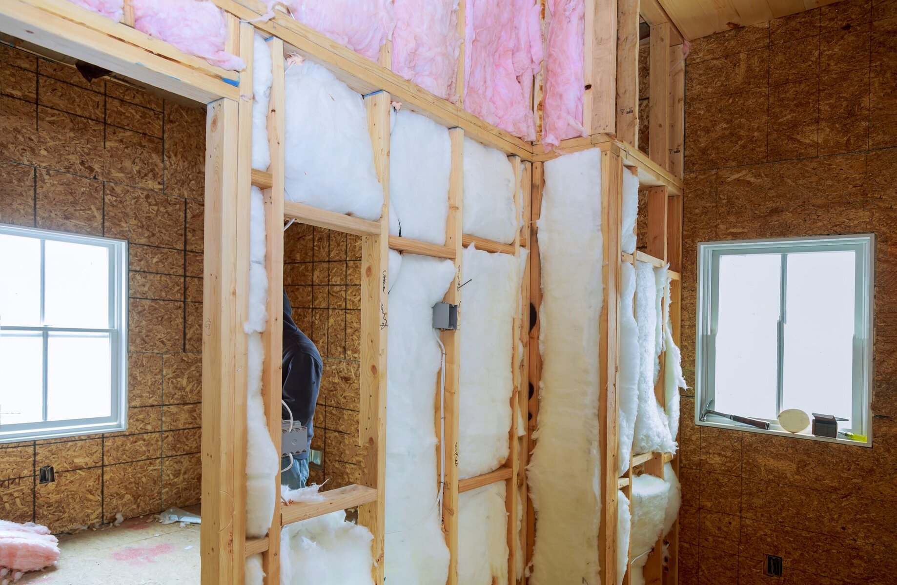 Interior view of a house under construction with insulation and wood framing
