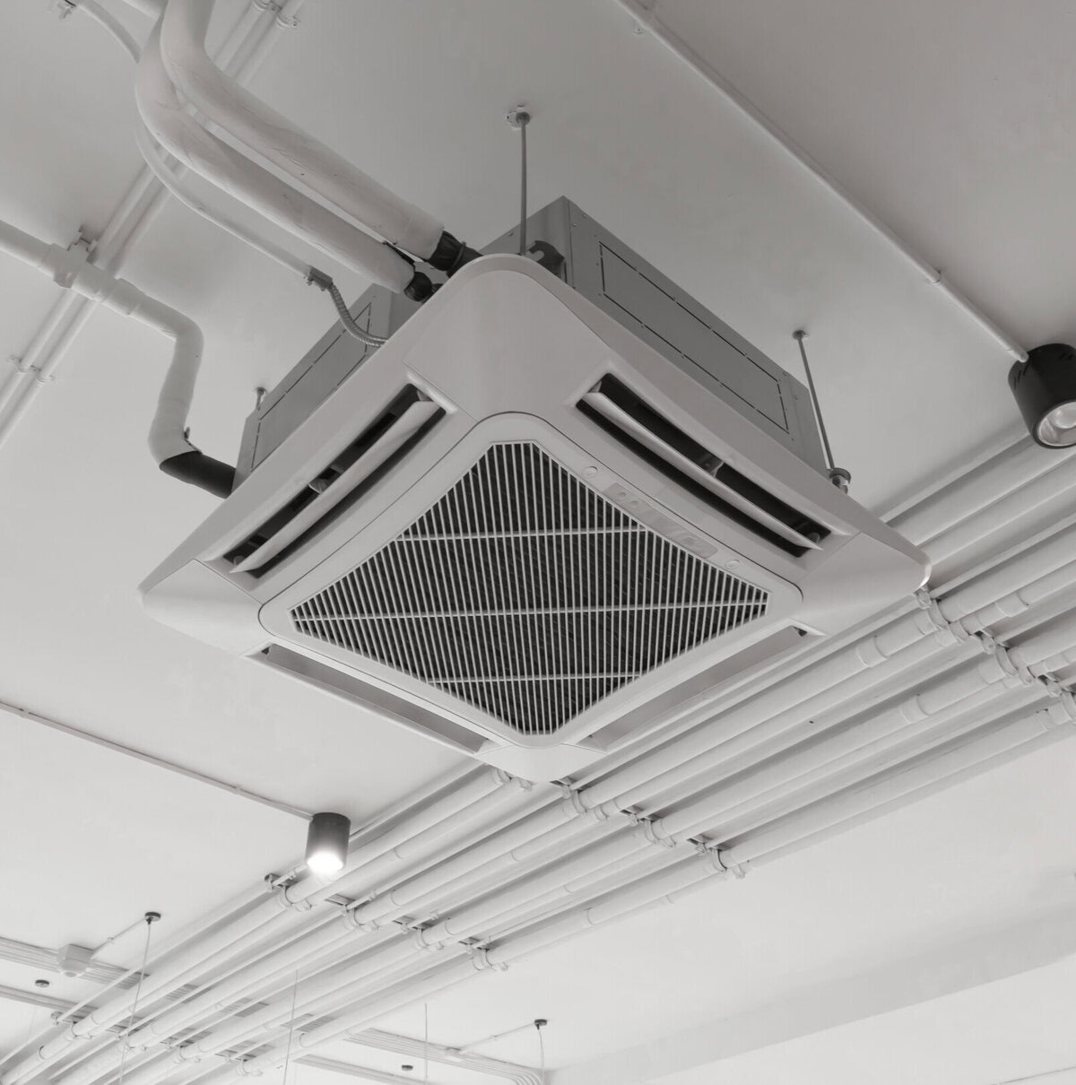 Ceiling-mounted air conditioning unit with visible ducts and lighting fixtures.