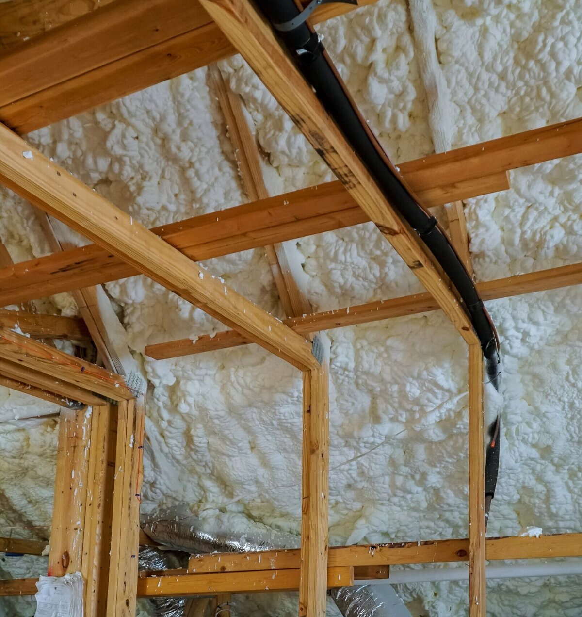 http://Spray%20foam%20insulation%20applied%20to%20the%20underside%20of%20a%20roof%20and%20wall%20framing.