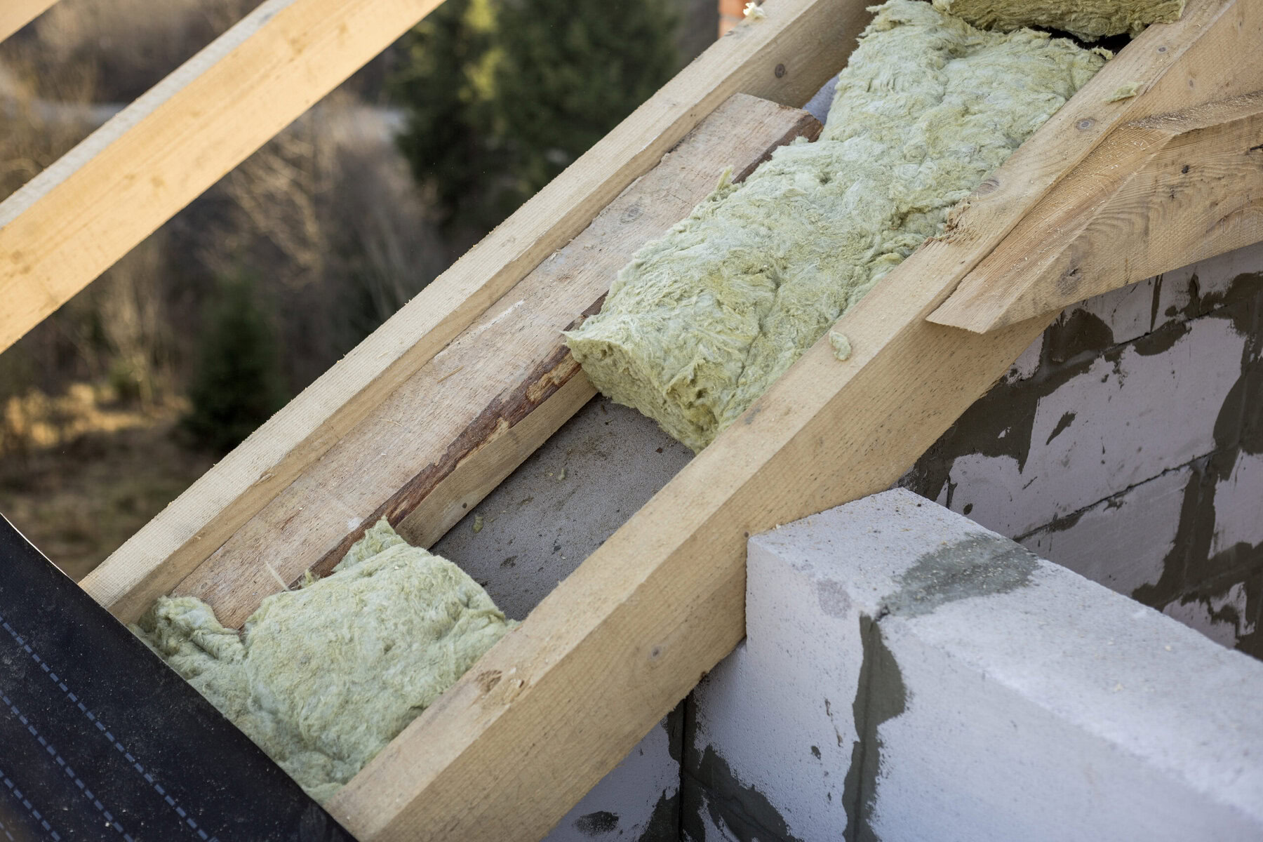 Roof insulation being installed on a wooden roof frame