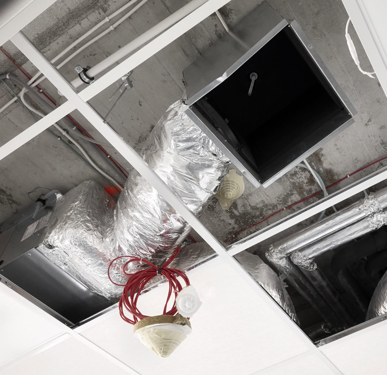 http://Exposed%20ceiling%20with%20ductwork,%20wiring,%20and%20a%20red%20coiled%20cable.