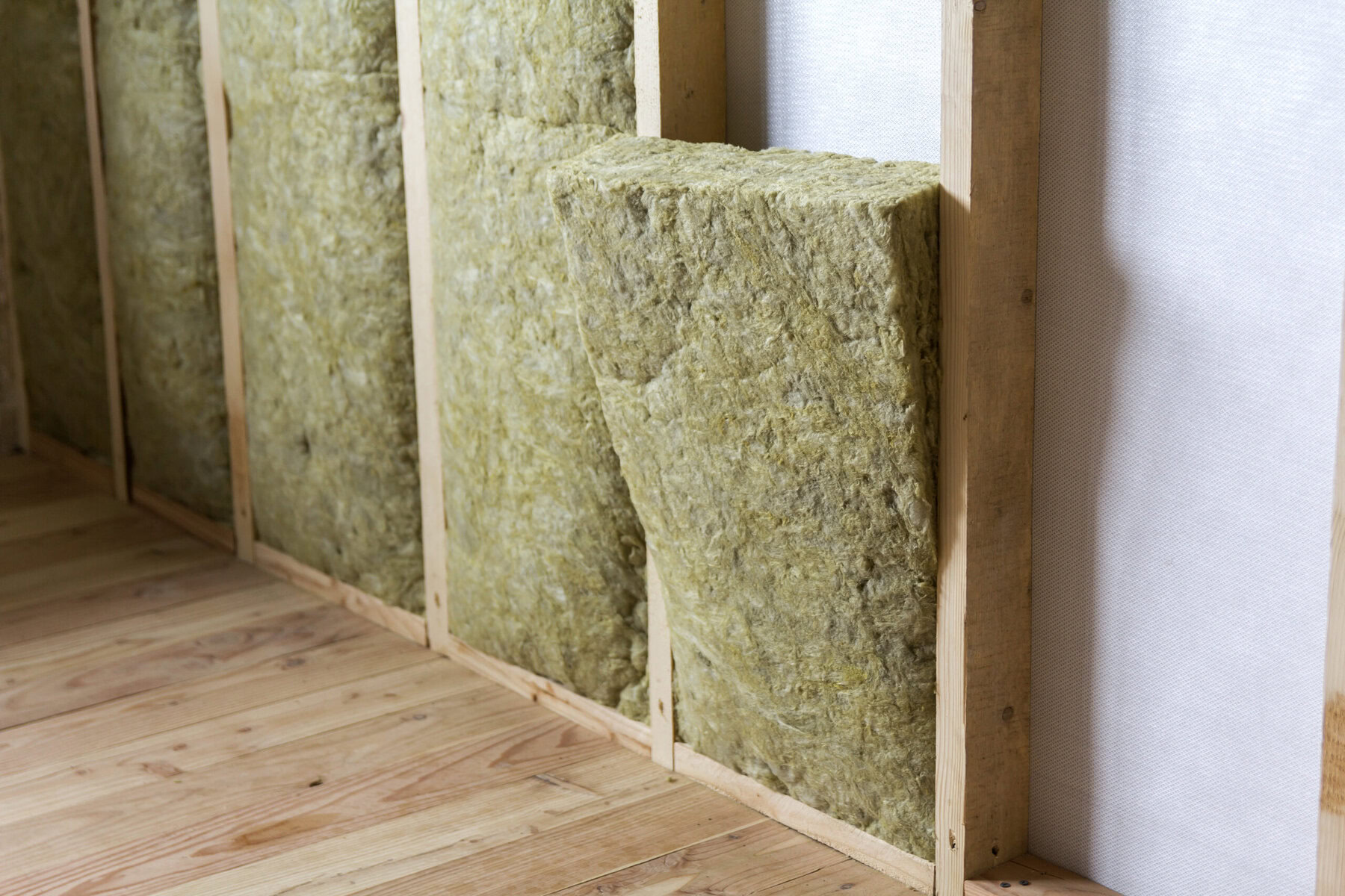 Insulation material between wooden studs in a wall.