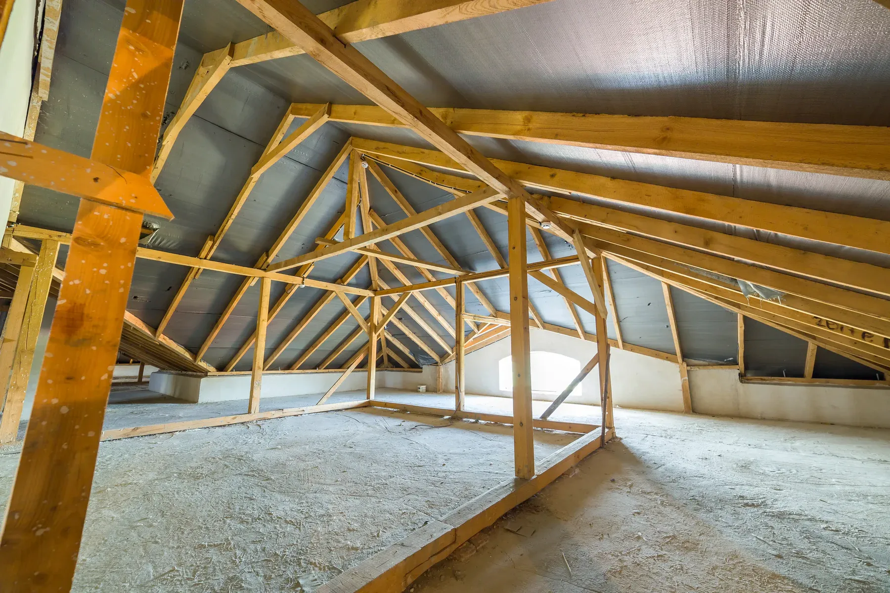 Unfinished attic interior with wooden beams and insulation