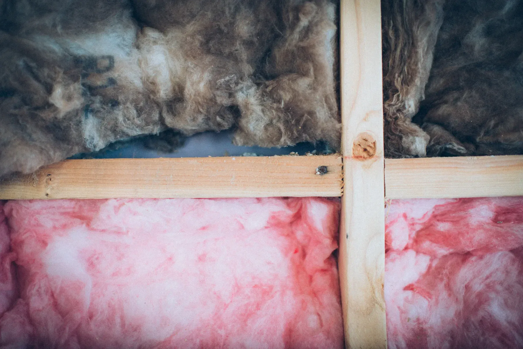 Close-up of pink and brown insulation with wooden beams.