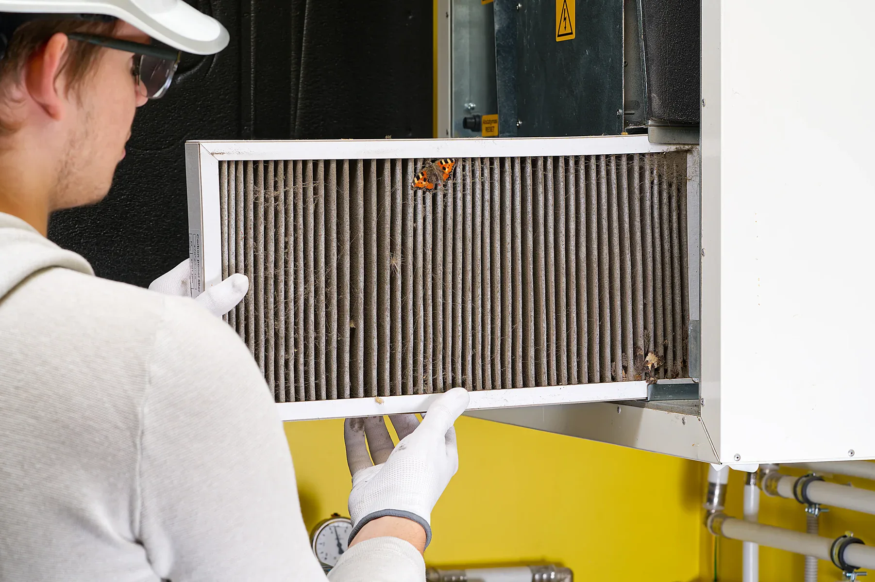 Man in safety glasses holding a dirty air filter with a butterfly on it.